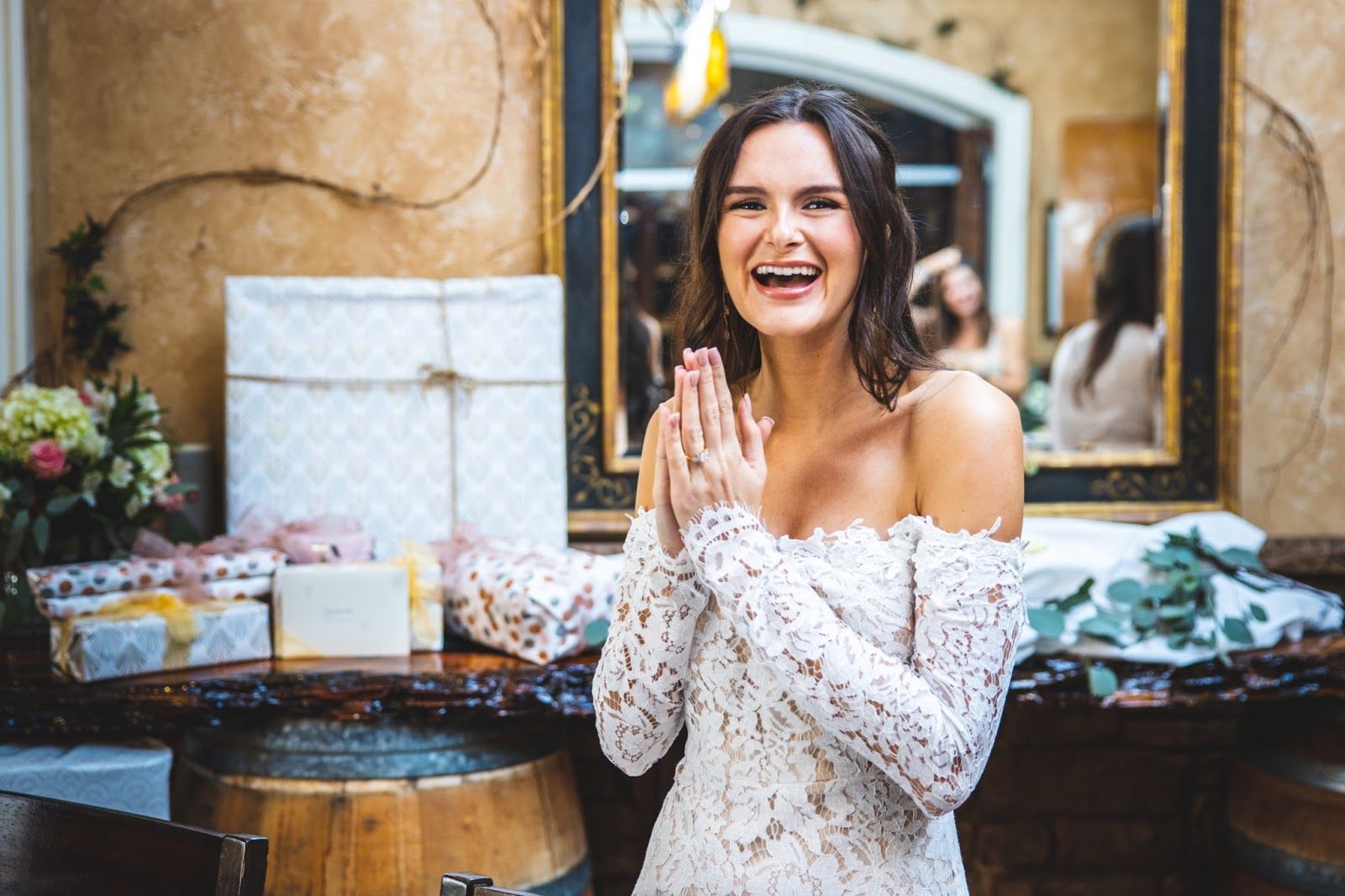 smiling bride standing in front of gift table with hands pressed together